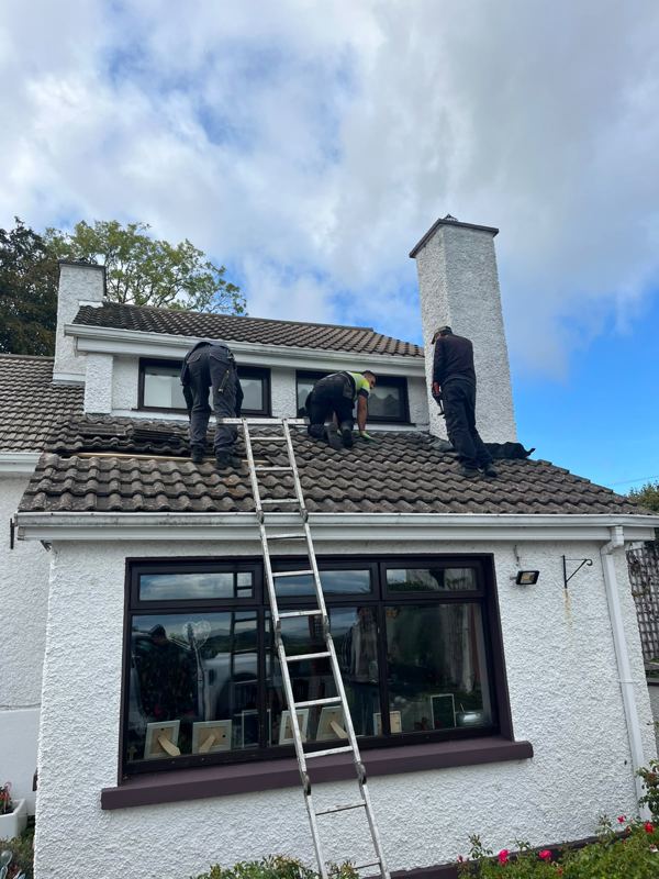 Roofers repairing a tiled roof on a Dublin house