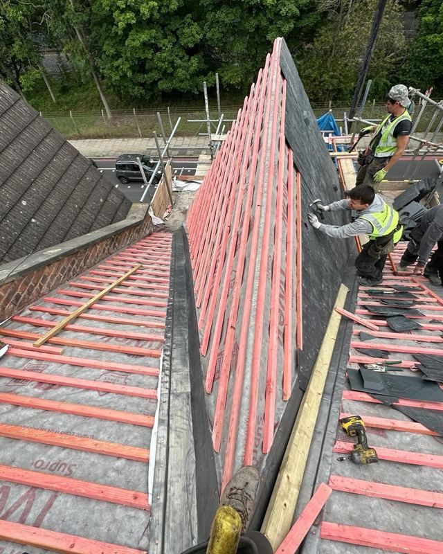 Roofers fitting new battens and slates during a re-roof