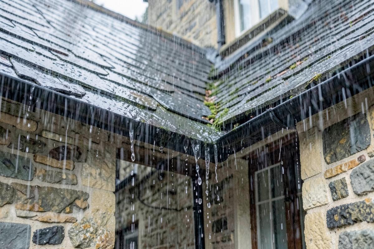 Heavy rain running off a slate roof and overflowing gutter