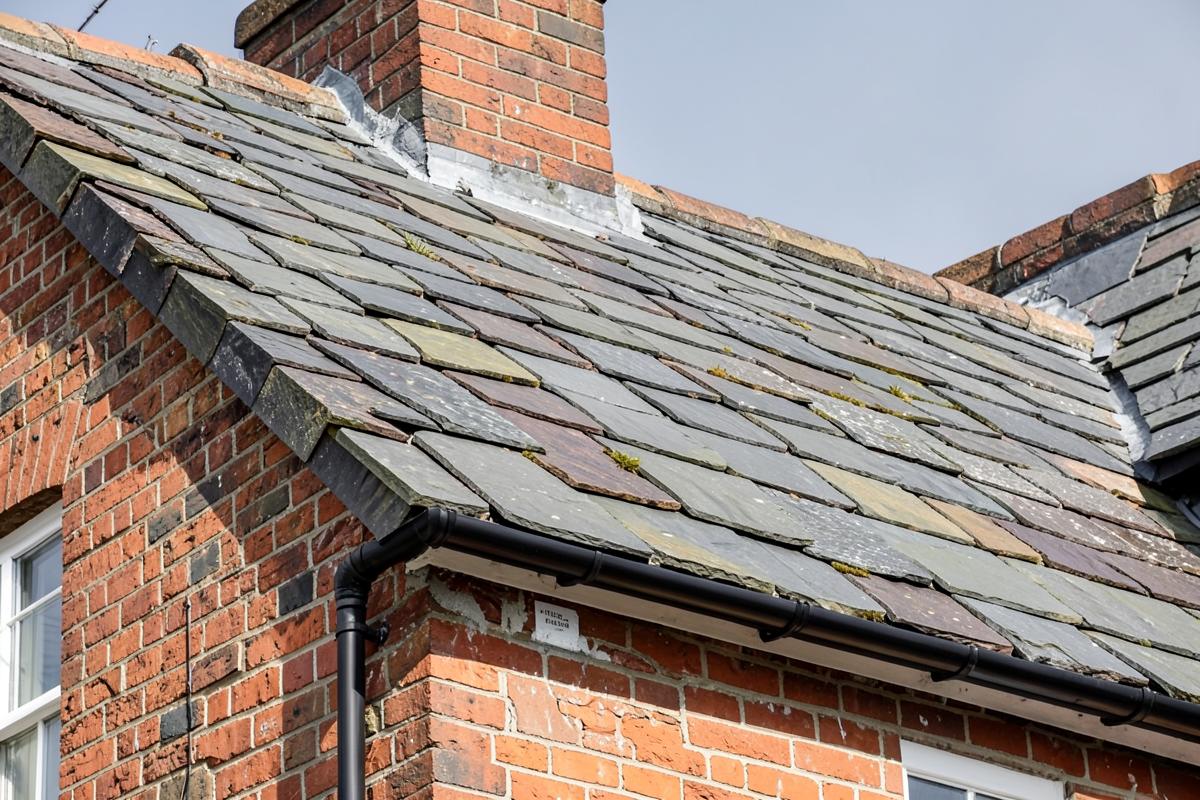 Natural slate roof on a red-brick house with repaired slate courses